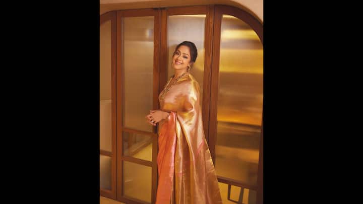 1. Jyotika: Jyotika looked stunning in a luxurious katan tissue silk saree that exuded elegance. The saree has intricate zari work and golden, peach colours. The actress paired her saree with a matching brocade blouse that enhanced the charm. She completed her outfit by adding a contrast with the long emerald necklace and matching earrings. (Image Source: Instagram/@jyotika)