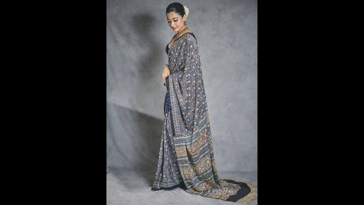 6. Rashmika Mandanna: Rashmika Mandanna stunned in a gorgeous Ajrakh print saree that had intricate geometric patterns and delicate embellishments. She paired it with a sleeveless blouse that had blue stone detailing and a plunging neckline. Rashmika completed her outfit with matching jewellery embedded with bluish stones that enhanced her look. (Image Source: Twitter/@iamRashmika)