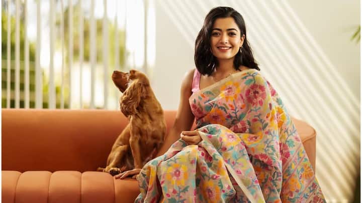 In a muslin hand-loom floral-weaved saree, Rashmika drapes herself in seeming grace. The pink sleeveless blouse blend matched the lighter shades perfectly, blending the touch with all simplicity and sophistication. (Image Source: Instagram/ rashmika_mandanna)