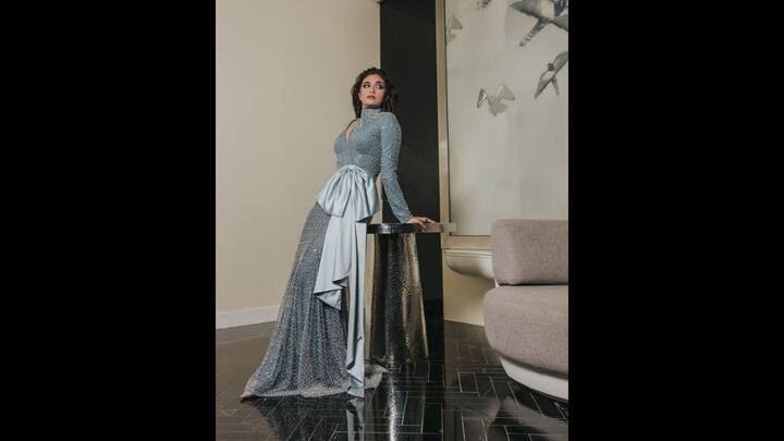 1. Long Shimmering Gown: Keerthy's long shimmering gown made her look glamorous. The gown had full sleeves with a high neckline. The figure hugging outfit had a huge satin bow detailing on it that gave a dramatic effect to the gown. The shimmering gown had silver embellishments and pearl detailing all over it for a mesmerising look. (Image Source: Instagram/keerthysureshofficial)