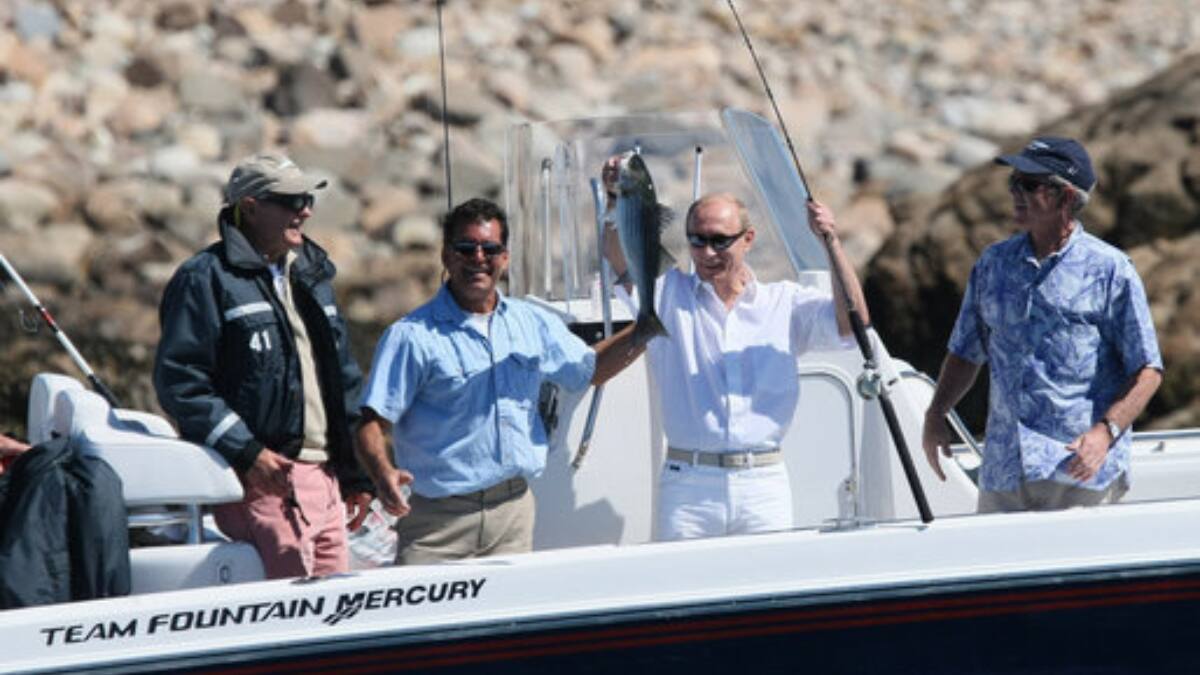 Vladimir Putin holds up his catch as George HW Bush and George W Bush look on | Photo: White House Archives