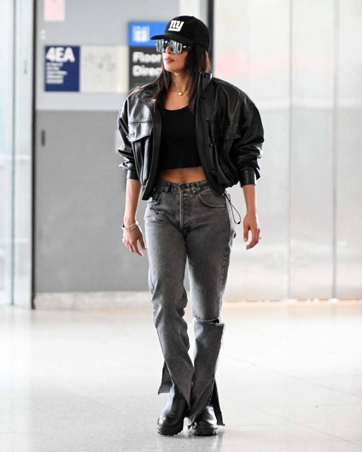 She accessorized with two dainty gold chains, one featuring a heart-shaped pendant, gold bracelets, rings, a black baseball cap, sunglasses, and black Chelsea boots.