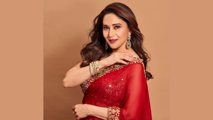 Madhuri Dixit looked iconic, draped in a red sheer saree with golden zari work and a heavily embellished blouse. An elegant wavy hairstyle, winged liner, and stud bindi look a picture of grace with the right touches for Navratri night. (Image Source: Instagram/ madhuridixitnene)