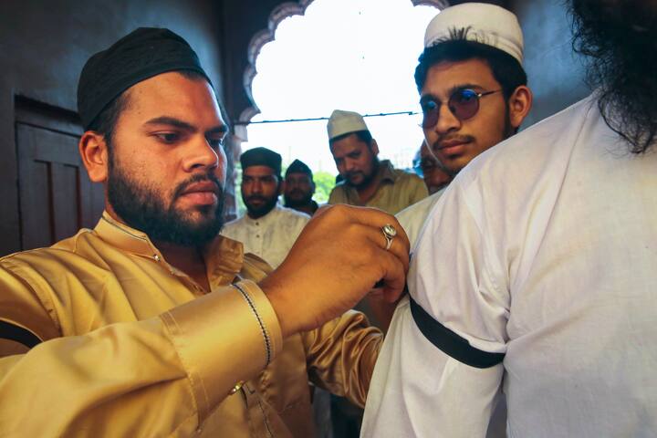 A Muslim devotee ties a black armband on another devotee as they arrive to offer 'namaz' on the last Friday of the holy month of Ramzan, at Taj-ul-Masajid, in Bhopal, Friday, March 28, 2025. The All India Muslim Personal Law Board has urged Muslims to wear a black band when they go for Juma prayers on the last Friday of Ramzan as a mark of their protest against the Waqf (Amendment) Bill. (Source: PTI)