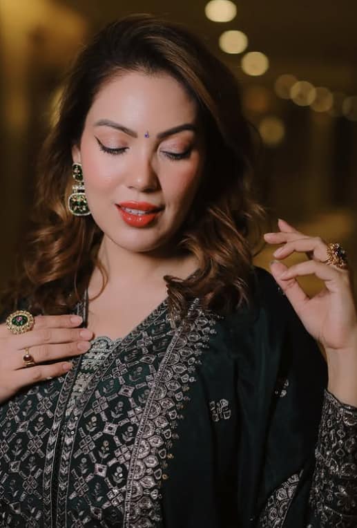 The actress is wearing a dark green color suit on which silver color embroidery has been done.