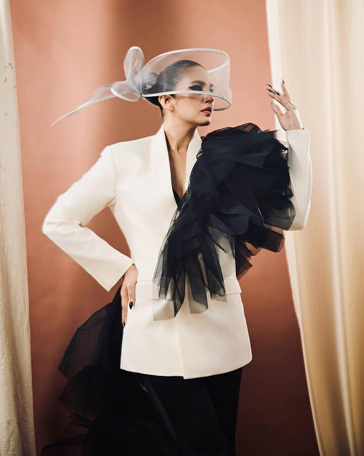 Adding a layer of mystery and elegance, Huma pairs the outfit with a sheer headpiece featuring delicate bow detailing.