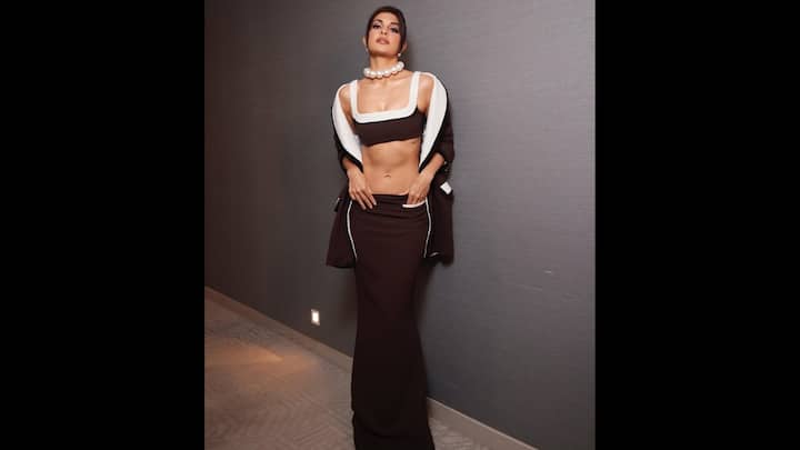 6. Bold Monochrome: Jacqueline Fernandez wore a striking dark coloured ensemble that featured a bralette, low waisted long skirt, and a matching jacket. The oversized jacket draped over the shoulder giving the actress a relaxed vibe. She paired her look with chunky peal necklace that added elegance to the attire. (Image Source: Instagram/@jacquelienefernandez)