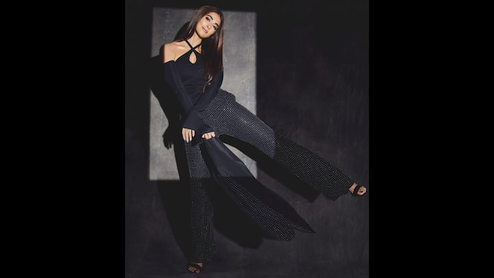 1. Glamorous All Black Look: Pooja Hegde wore a chic off shoulder black top with crisscross detailing. She paired her top with a shimmering wide leg pants. The bold and elegant look was elevated with minimal accessories and strappy heels that are perfect for stylish evenings. (Image Source: Instagram/@hegdepooja)