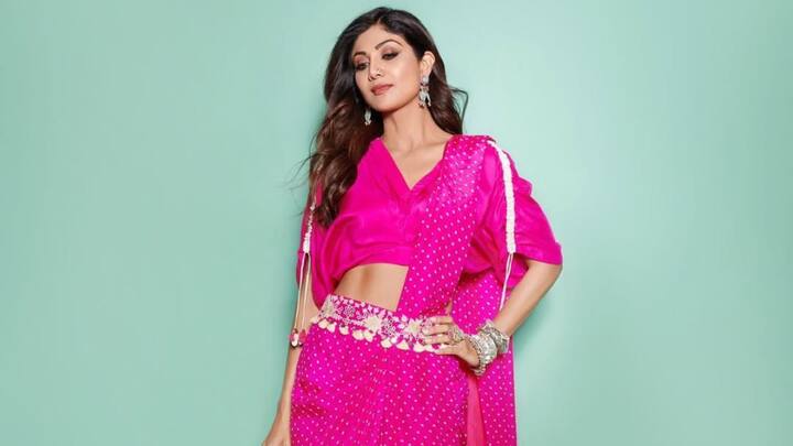 Shilpa Shetty, embracing modernity with this hot pink pre-draped concept Bandhani saree, flaunted a kaftan-style blouse with an embellished belt, barely accessorising as she let the distinct design do all the talking. (Image Source: Instagram/ pinkcitybysarika)