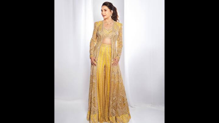 8. Yellow Three Piece Suit: Madhuri Dixit dazzled in a radiant yellow embroidered suit set that featured a bralette, palazzo pants, and a long ornate jacket. The intricate detailing on the ethnic fit gave a festive and luxurious look. The actress completed her attire with minimal jewellery that added a touch of contemporary charm. (Image Source: Instagram/@madhuridixitnene)