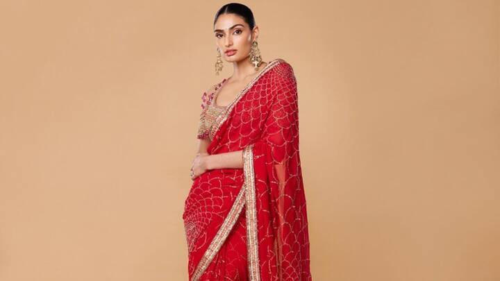 Athiya's red and gold georgette saree with subtle patterns and gold borders oozes traditional elegance. Given a tulle blouse and a sleek bun, this is the perfect polished and festive look for the morning puja. (Image Source: Instagram/ athiyashetty)