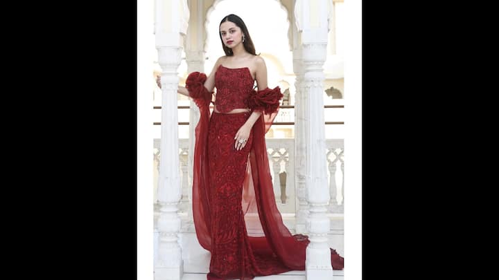 2. Floral Red Attire: Nitanshi Goel looked like a modern-day princess in her exquisite red outfit that blended traditional artistry with contemporary styles. She wore a corset-style strapless blouse with rich rich embellishments. The actress paired her blouse with a long and sleek skirt with matching embroidery. The sheer dupatta-style drapes cascading from her arms had 3D floral accents that set her outfit apart. To complete her look, she wore statement ear cuffs and rings that elevated her look. (Image Source: Instagram/@nitanshigoelofficial)