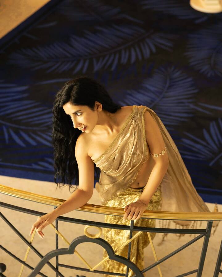 पारुल ने गोल्डन कलर की बनारसी टिशू साड़ी पहनी है. इसके साथ उन्होंने मैचिंग ऑफ शोल्डर ब्लाउज पेयर किया है.