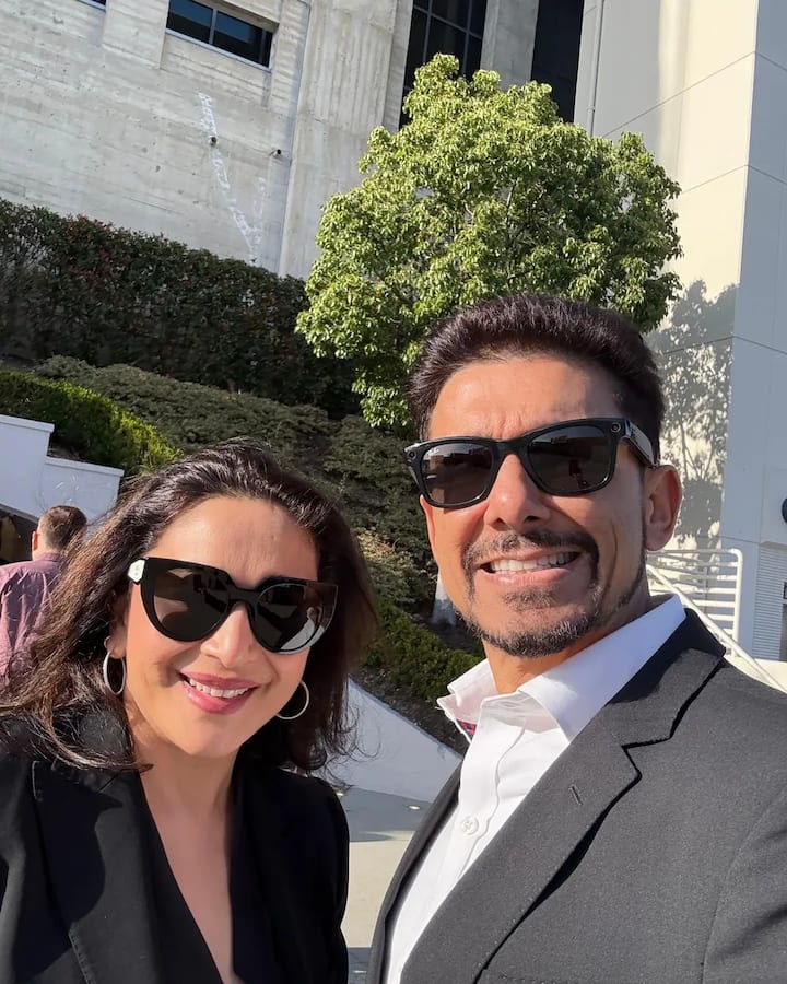 Madhuri looks stylish in white and black pants and black sunglasses.