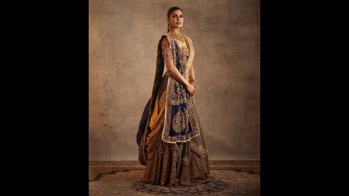 5. Royal Ensemble: Jacqueline Fernandez looked ethereal in her lehenga crafted with intricate artistry. The embellished blouse with intricate zardozi work, paired with a luxurious lehenga skirt with sequins and rich embroidery. She styled her look with statement gold jewellery that includes a heavy choker, jhumkas, bangles, and rings. Her traditional lehenga channeled a vintage royal aesthetic, making it ideal for grand festivities or celebrations. (Image Source: Instagram/@jacquelienefernandez)