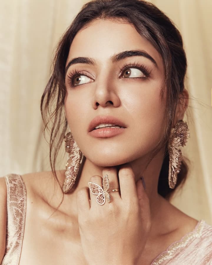 Her makeup, crafted by Vaishnavi Soni, highlights her natural beauty with a radiant dewy base, soft earth-toned eyes, and rose-tinted lips, creating a flawless soft-glam effect.