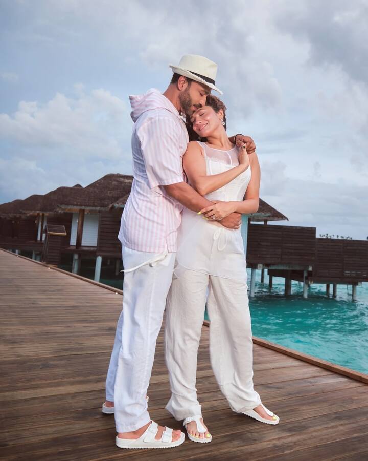 Ankita stuns in a sheer white dress featuring an asymmetrical hem, paired with flowing loose-fit trousers.