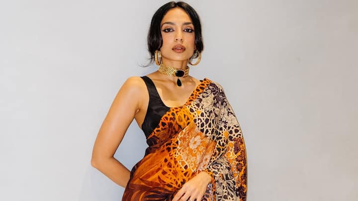 Going dramatic, Sobhita donned this safari-printed saree with a sleeveless black blouse. Her chunky gemstone neckpiece and golden hoops gave this bohemian ethnic ensemble a fierce, fashion-forward twist. (Image Source: Instagram/ sobhitad)