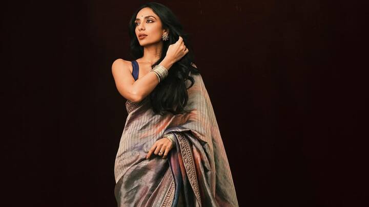 She looked effortlessly chic in this semi-transparent black and white saree that featured intricate embroidery and abstract prints. Paired with a black strappy blouse and bold sunglasses, it was the perfect mix of minimal and tough. (Image Source: Instagram/ sobhitad)