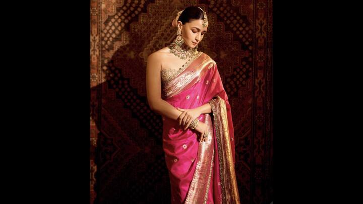 7. Alia Bhatt: Alia Bhat opted for a stunning hot pink saree which featured rich golden zari work and embroidered motifs. The contrasting gold pallu added depth to the outfit. The strapless blouse added a modern touch to the traditional fit while the gold jewelley pieces enhanced the outfit's regality, giving Alia an opulent and culturally rooted look. (Image Source: Twitter/@softiealiaa)