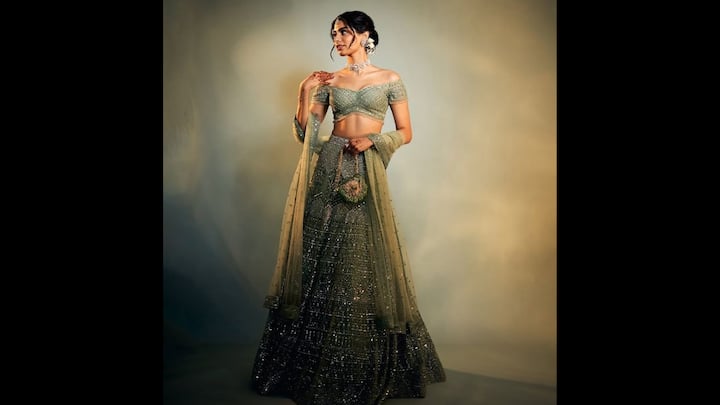 8. Khushi Kapoor: Khushi Kapoor wore a dazzling pastel green lehenga that gave her an opulent look. The heavily embellished ensemble was full of fine sequins, mirror work, and floral thread motifs. The off shoulder blouse flattered her frame and gave her a youthful, regal vibe. She paired her fit with a sheer dupatta that had beaded detailing for an ethereal finish. To accessorise her look, she wore a floral choker neck piece with matching earrings. Khushi completed her look with a matching and heavily studded handbag which made her look trending. (Image Source: Pinterest/debbieoare)