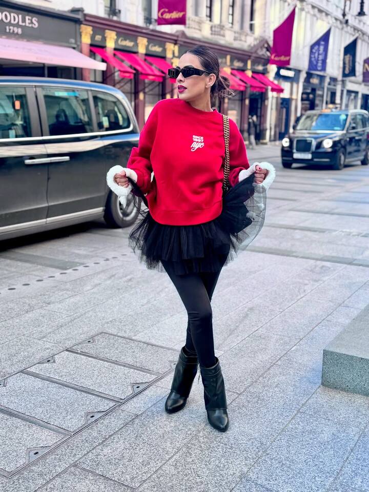 The diva posed on the street for some stylish clicks in a black dress with frills underneath a red sweatshirt, paired with black leggings, matching shoes and handbag.