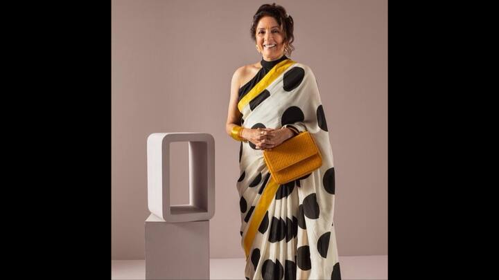 1. Retro Saree Look: Neena Gupta draped a classic white saree which had oversized black polka dots all over it. She embraced retro glamour with a modern twist. The striking mustard yellow border added the right amount of pop to the ensemble. Styled with a chic, sleeveless black blouse, featuring a high neckline, the outfit blended grace with confidence. She complemented her traditional look with a mustard-hued textured handbag. Keeping the jewellery minimal she served an impactful look. (Image Source: Instagram/@neena_gupta)