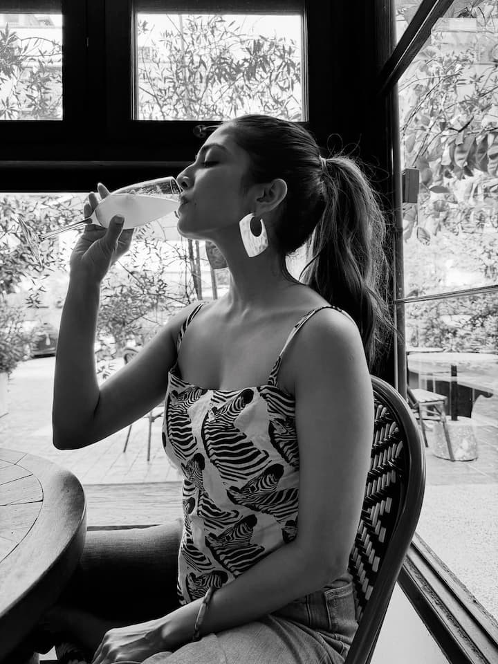 Dressed in a monochrome printed handkerchief-style crop top with delicate tie-back detailing, Malavika adds a playful yet elevated touch to the casual outfit. The asymmetrical cut of the top flatters her frame and brings in a Y2K flavor—effortless yet fashion-forward.
