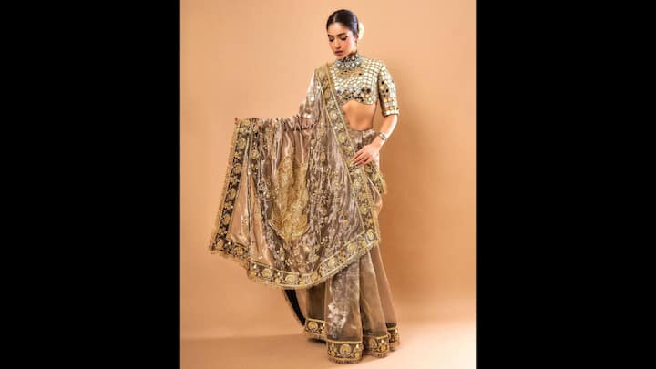 4. Bhumi Pednekar: Draped in a rich lehenga ensemble, Bhumi redefined traditional fashion with a luxurious twist on mirror work styling. With its high neckline, structured shoulders, and intricately placed mirror detailing, the blouse exudes a warrior-princess vibe while maintaining a modern couture edge. Paired with a deep gold-toned lehenga featuring textured velvet, ornate zari embroidery, and bold floral borders, the outfit spoke volumes of craftsmanship and grandeur. Her sleek bun with a gajra, bold eye makeup, and statement choker added to the regal energy of the look. Bhumi’s ensemble is a perfect inspiration for brides, festive attendees, and anyone looking to make a jaw-dropping entrance. (Image Source: Instagram/@bhumipednekar)