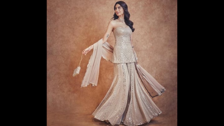 7. Khushi Kapoor: Khushi Kapoor wore dazzling champagne-hued sharara set. The young fashionista's outfit featured flared sharara pants that flowed with grace and shimmered with every move, capturing the essence of traditional craft in a bold, modern silhouette. The delicate dupatta, sprinkled with reflective accents and a scalloped border, added the right touch of elegance without overpowering the look. Styled with minimal jewellery, soft waves, and a sparkly potli bag, Khushi’s outfit is a masterclass in youthful ethnic styling. (Image Source: Pinterest/Cath_iee)
