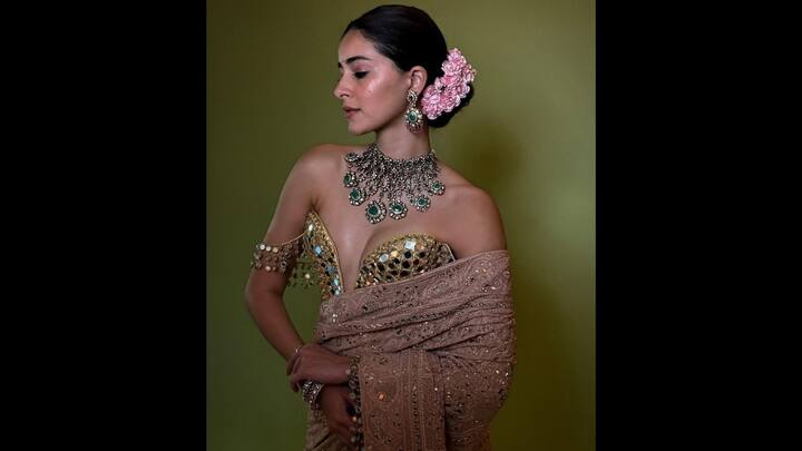 3. Ananya Panday: Ananya turned up the glam quotient in a stunning mirror work attire. This statement ensemble combined traditional craftsmanship with bold styling, making it a perfect pick for modern-day divas who love drama with elegance. The look featured a gold mirror-encrusted blouse with a sculpted sweetheart neckline and dramatic off-shoulder sleeves adorned with reflective tassels. Paired with a blush-toned lehenga, the fit was full of intricate threadwork and sprinkled mirrors. The actress accessorised her attire with a regal emerald-encrusted choker and statement earrings, that made her look opulent. (Image Source: Pinterest/@vogueindia)