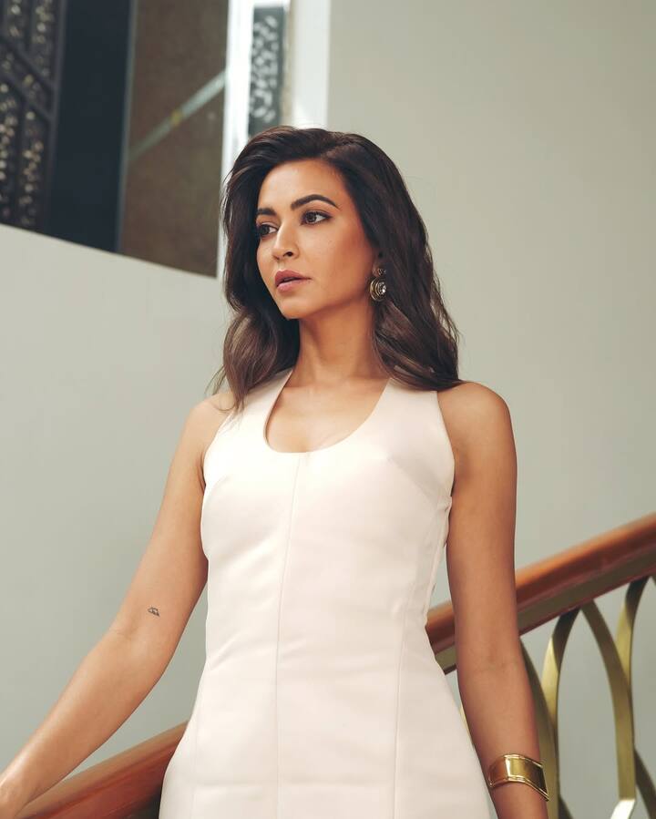 The outfit—a structured ivory sleeveless top paired with a voluminous, flowing skirt—strikes a balance between modern chic and classic drama. The clean lines of her top flatter her figure while the exaggerated skirt adds drama to the silhouette.