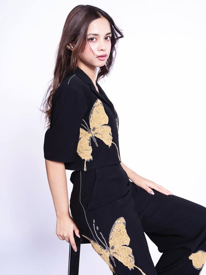 The co-ord set features a black base adorned with luxe golden floral prints, giving the outfit a rich, festive edge. The cropped top showcases a fitted silhouette with delicate straps, highlighting her toned frame and adding a subtle yet confident vibe.