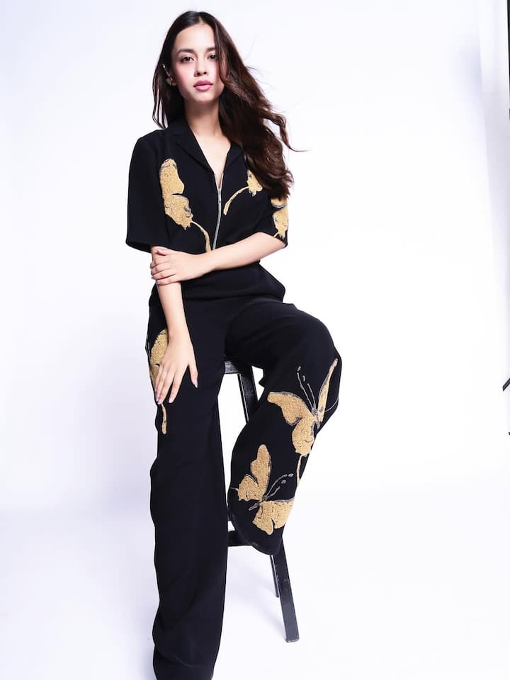 Her soft curls cascade effortlessly, adding a romantic touch to the outfit, while her makeup remains fresh and radiant—with dewy skin, subtly defined eyes, and a soft nude lip that complements the golden accents perfectly.