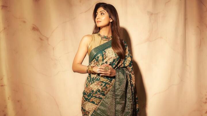 Shilpa Shetty wore this green and gold saree with detailed Zari work, accompanied by a golden sleeveless blouse. She finished off her look with matching accessories in earthy golden hues. (Image Source: Instagram/ theshilpashetty)