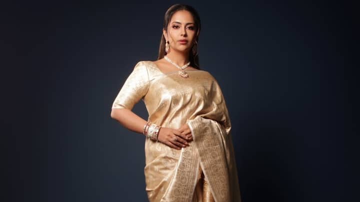 This golden saree with elaborate detailing and a lightweight blouse looks ethereal. The pearl jewellery set and the half-tied hairdo add to the ethnic beauty with ease. (Image Source: Instagram/ avikagor)