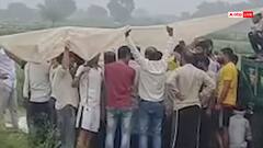 Watch: तेज बारिश के बीच तिरपाल पकड़कर कराया महिला का अंतिम संस्कार, हैरान कर देगा मथुरा का वायरल वीडियो