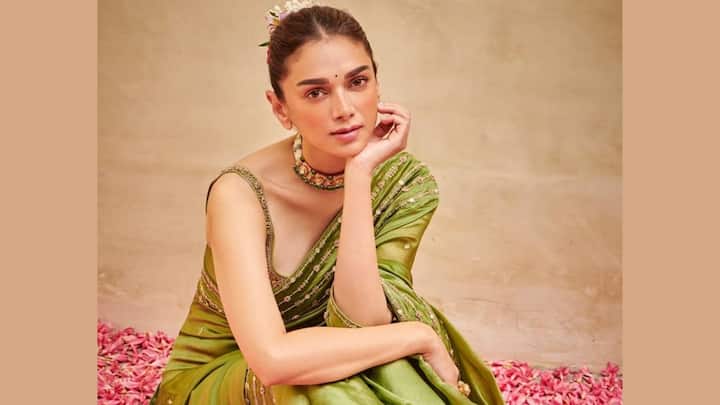 Aditi dazzled in this green organza silk saree with a backless sleeveless blouse. A pearl choker, a bun adorned with flowers, and dewy makeup were the perfect accessories that complemented her minimalistic desi beauty. (Image Source: Instagram/ aditiraohydari)