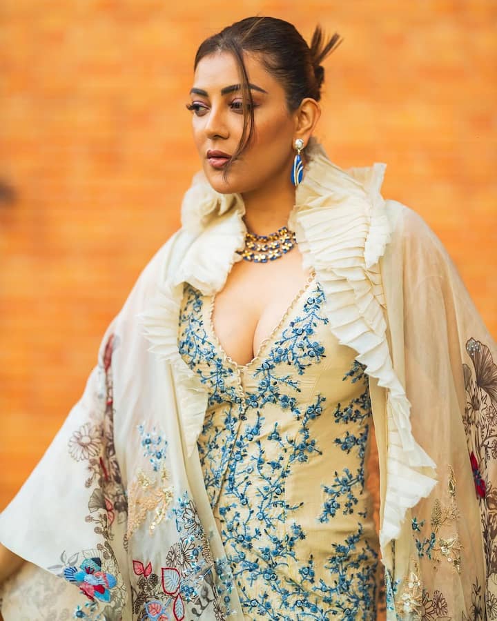 Kajal has paired the off white deep neck dress with a matching designer shrug. Matching jewellery is making her look more stunning.