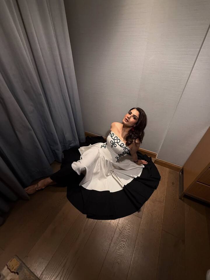 Cinched at the waist, the dress cascades into a flowing skirt with a striking black hem.