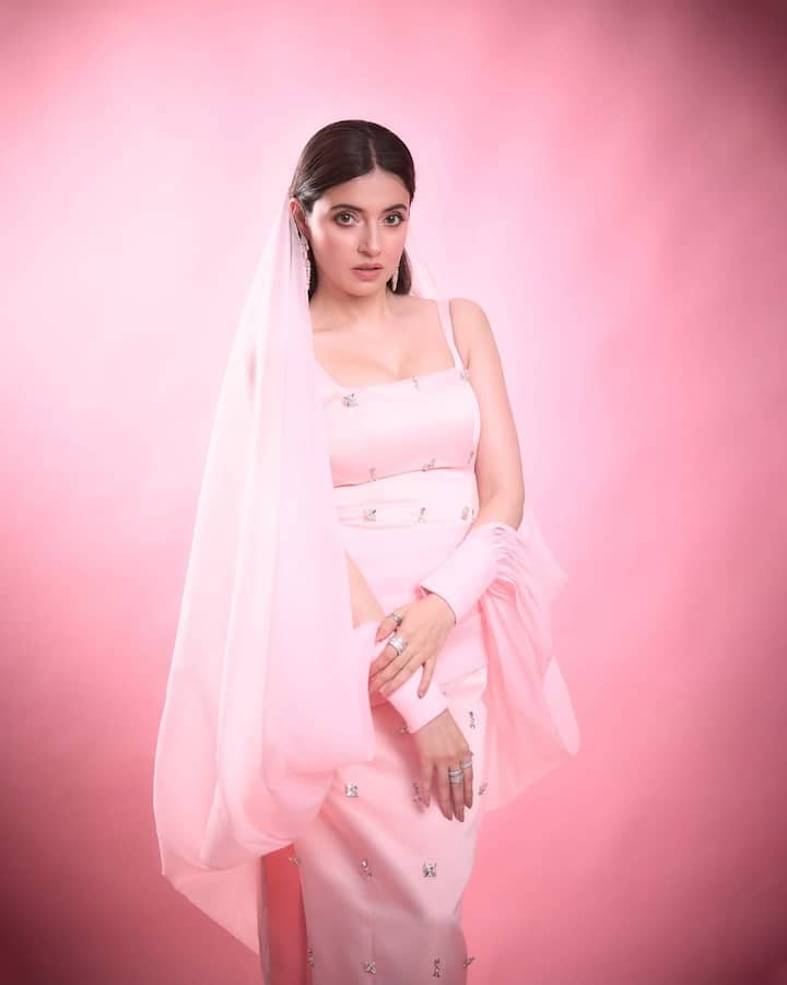 Her eyes are defined with precision, framed with dramatic lashes and just the right amount of kohl. The glossy finish on her lips paired with luminous skin creates a porcelain-doll effect that enhances the Barbiecore vibe of the look.