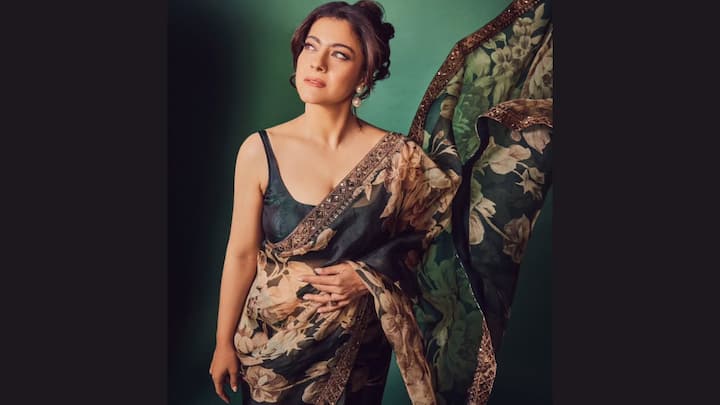 Adorned in this dark green saree with soft floral prints in earthy shades, Kajol paired it with a matching sleeveless blouse. Pearl earrings and a sleek bun created the perfect understated yet glamorous festive look. (Image Source: Instagram/ kajol)