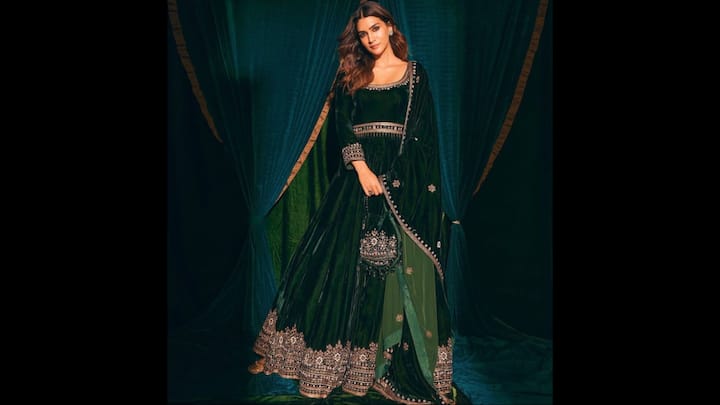 1. Green Velvet Anarkali: Velvet has made a royal comeback, and Kriti proved why it’s the ultimate choice. Dressed in deep forests green, this exquisite Anarkali set featured luxurious velvet and intricate zari embroidery. The ensemble was elevated by a matching dupatta with delicate floral motifs that perfectly shimmered. Kriti Sanon’s soft waves, minimal makeup, and statement earrings allowed the outfit to shine, making this look an impeccable choice for Hariyali Teej. (Image Source: Pinterest/nathanrathi)