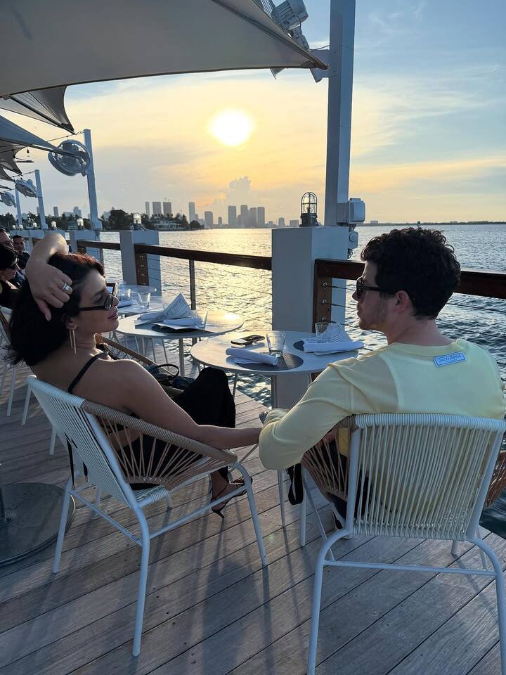 Priyanka posed in black with a serene expression, set against a sunny Miami skyline, exuding calm confidence.