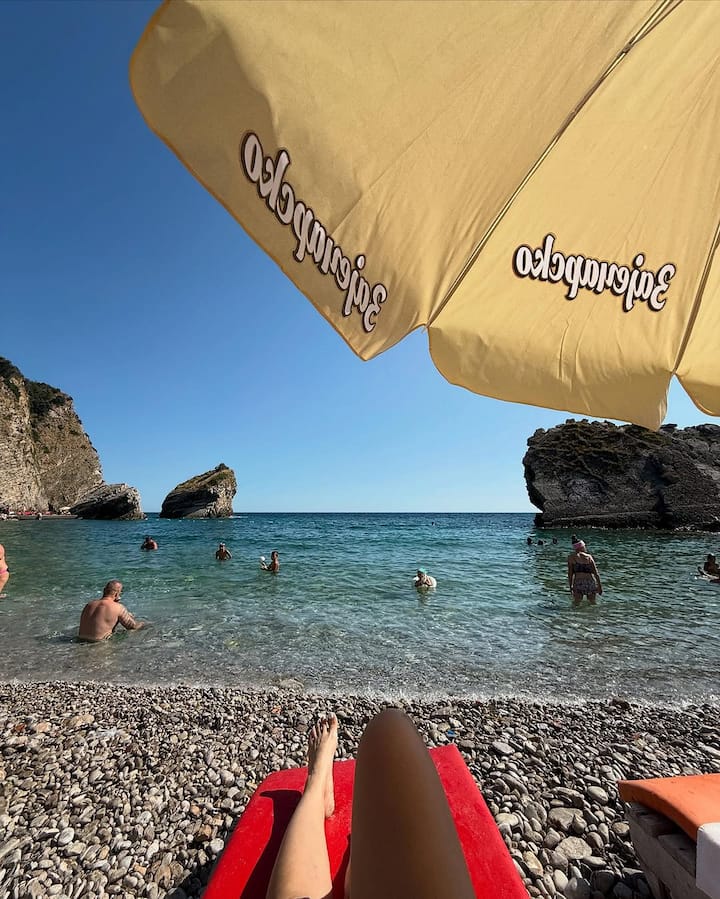 She wore a stylish bikini ensemble featuring a white floral balconette top and cobalt blue bottoms, accessorised minimally with sunglasses and beach essentials.