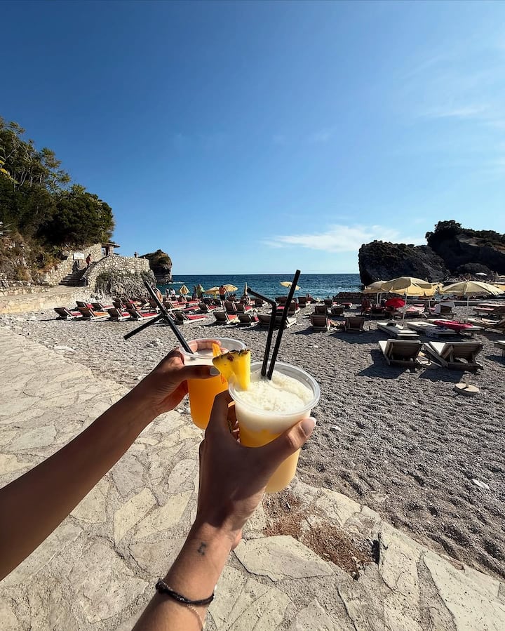 A mustard tote, tropical drink, and baseball cap brought playful color and personality to her vacation snaps.