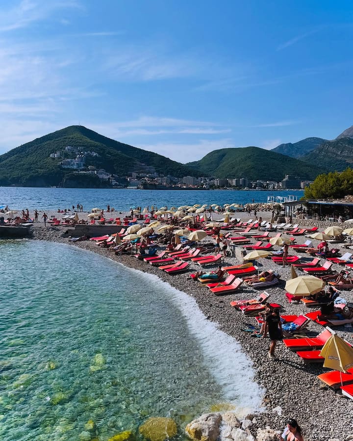 The scenic setting includes the turquoise waters of the Adriatic Sea, rugged cliffs, and a serene cove that adds to the dreamy vibe of her getaway.