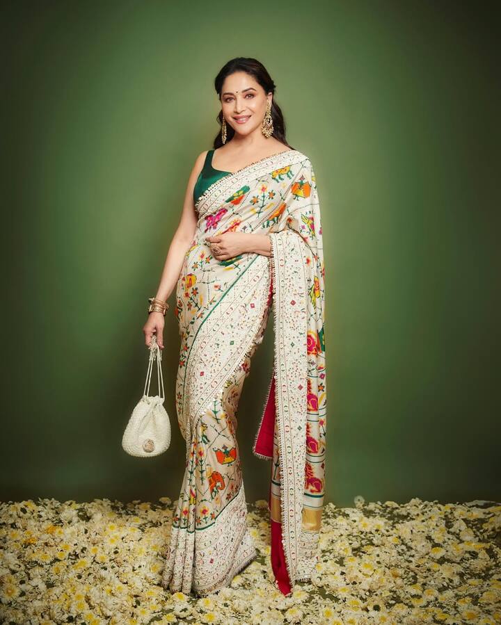 माधुरी दीक्षित का ये लुक काफी हटकर है. ऑफ व्हाइट के साथ ये मल्टीकलर के फ्लावर साड़ी को और खूबसूरत बना रहे हैं. माधुरी ने इसे ग्रीन कलर के कंटरास्ट ब्लाउज के साथ कैरी किया है. उन्होंने अपने लुक को सिंपल रखते हुए सिर्फ हैवी ईयररिंग पहने हैं. जिसमें वो बेहद प्यारी लग रही हैं.