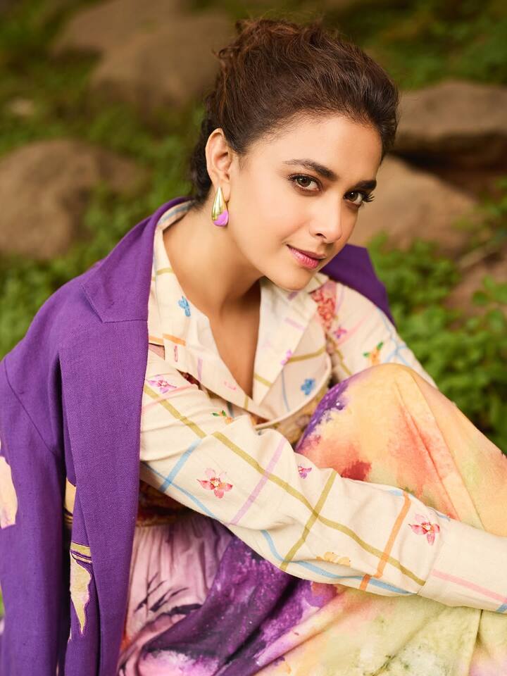 Keerthy opts for purple-hued glass drop earrings, mirroring the tones in her coat.