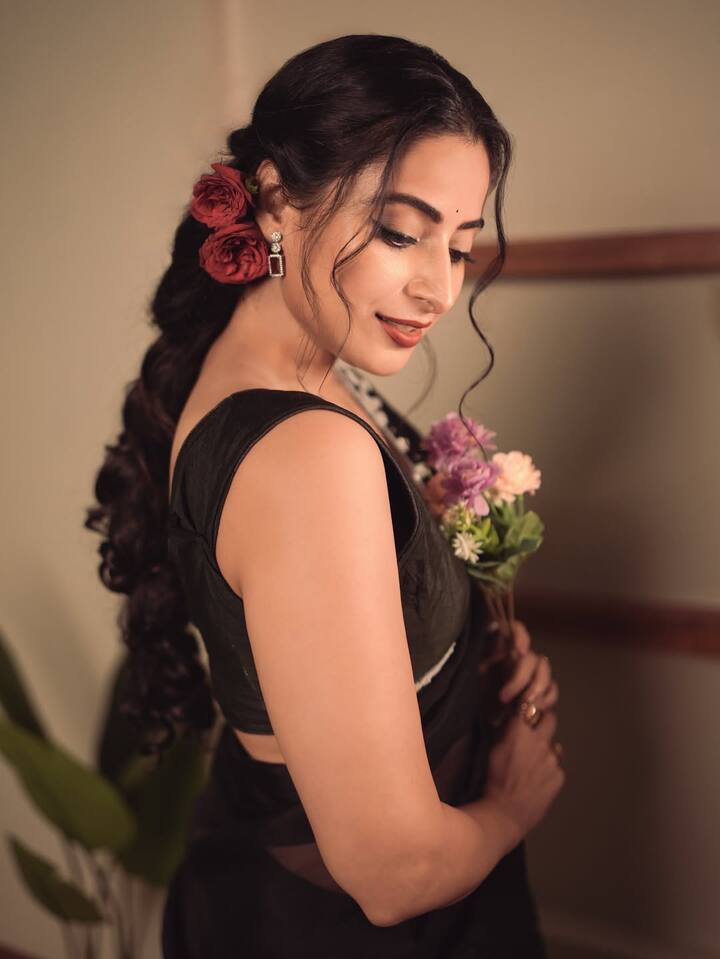 She’s styled her hair into soft retro waves gathered to one side, accentuated with deep red roses.